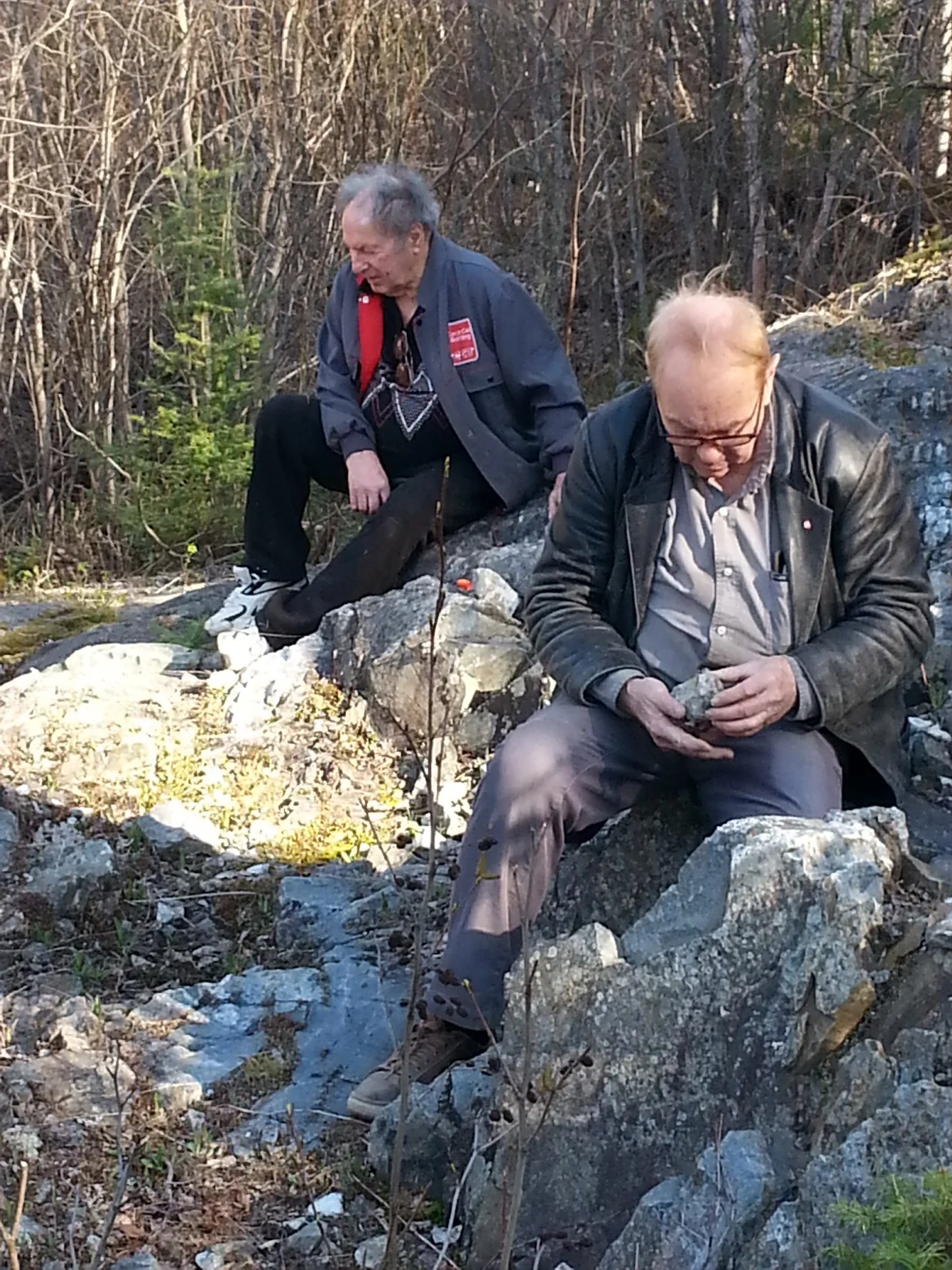Bob Young and Herb Funk examining quartz veining in a rocky field area in 2017.
